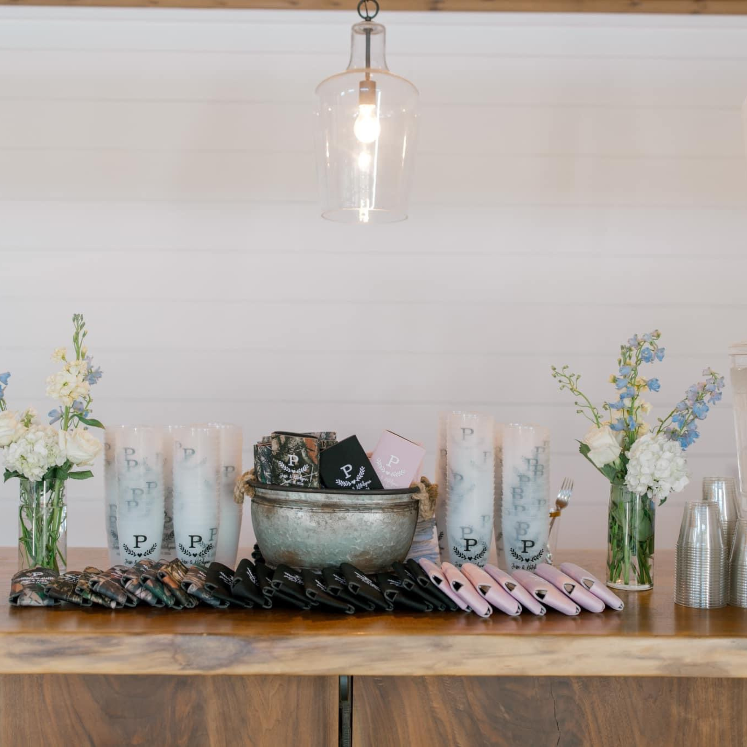 Decorative table setup with floral arrangements, candles, napkins, and cups for an event.
