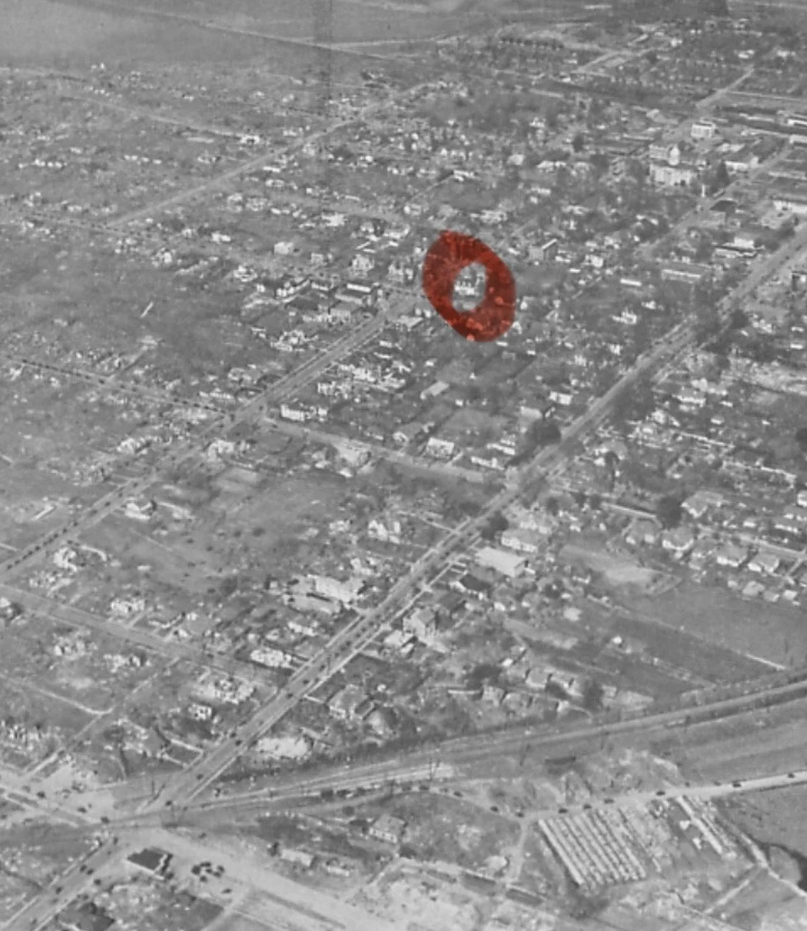 Aerial black and white image of a residential neighborhood with a red circle highlighting a specific house.