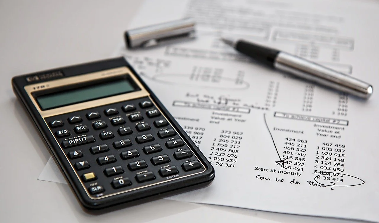 Calculator, pen, and financial documents with handwritten notes and circled figures on a table.