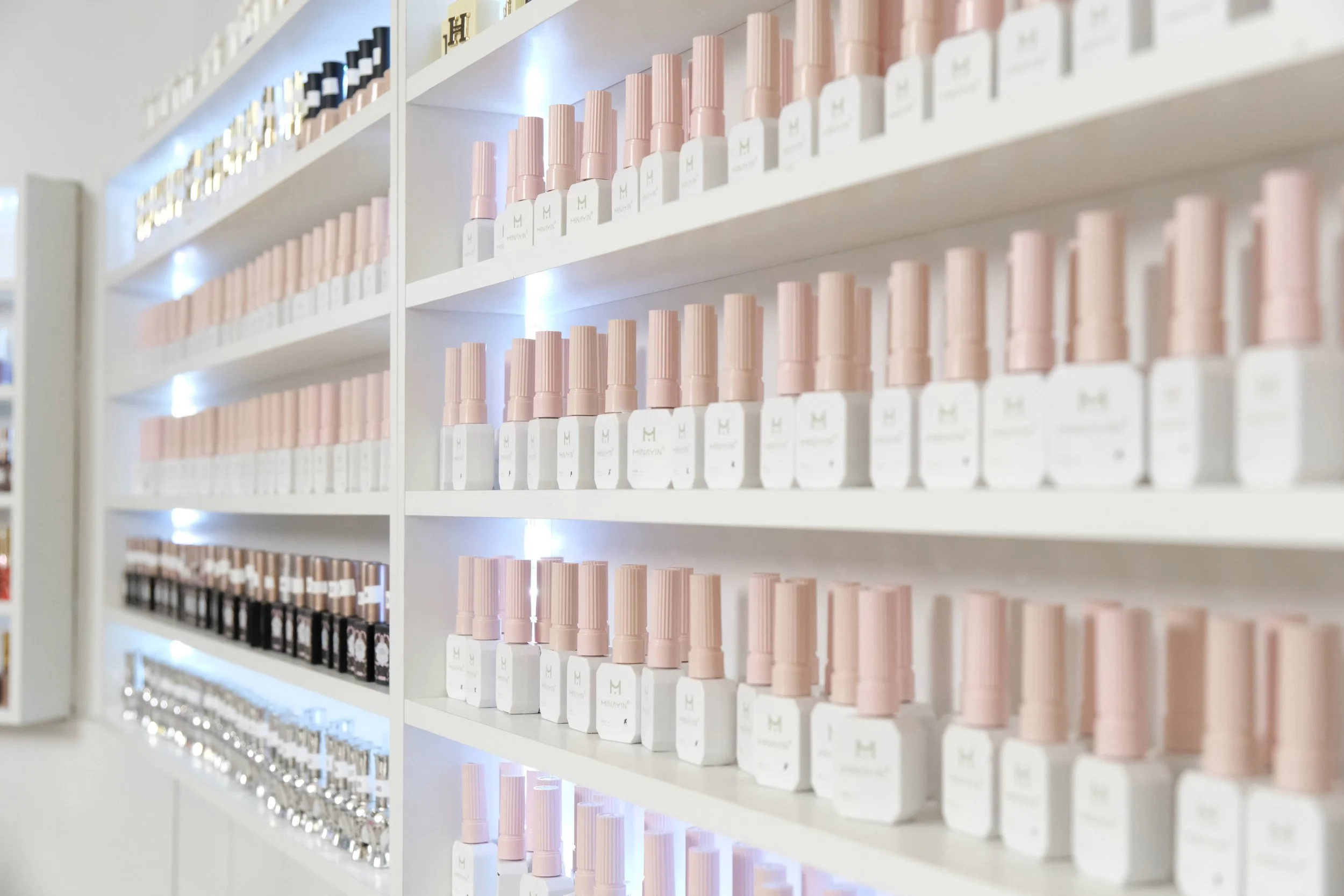 Regale mit mehreren Reihen von Nagellackflaschen in verschiedenen Farben in einem Schönheitsgeschäft.