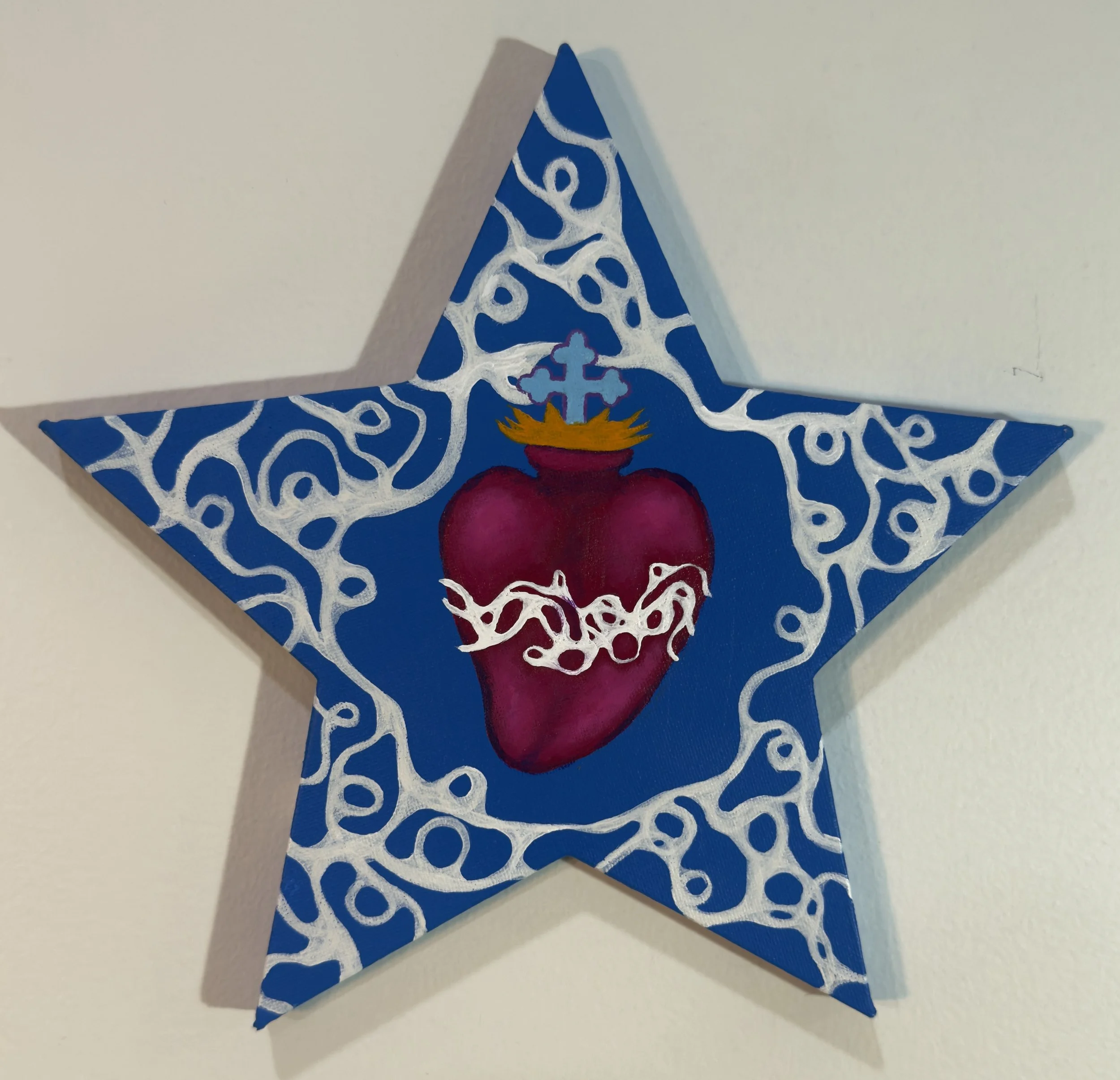 Star-shaped artwork with a red anatomical heart at the center, surrounded by white decorative patterns, against a blue background.