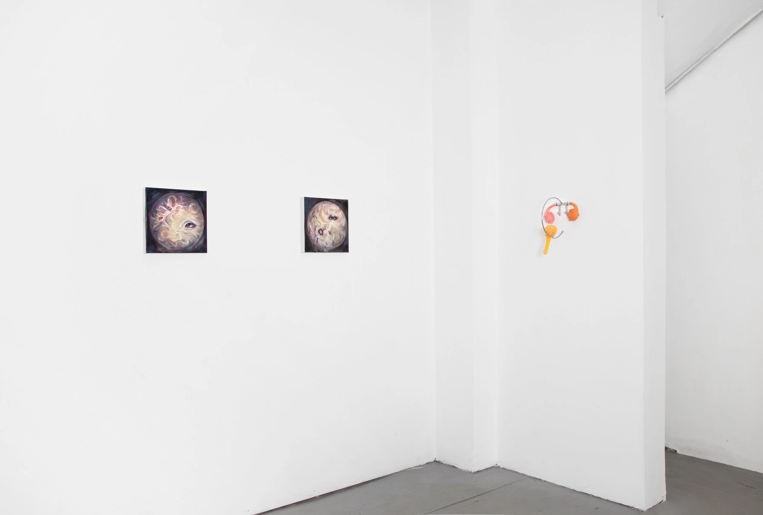 Art gallery white walls with two framed abstract paintings and a small sculpture on the right.