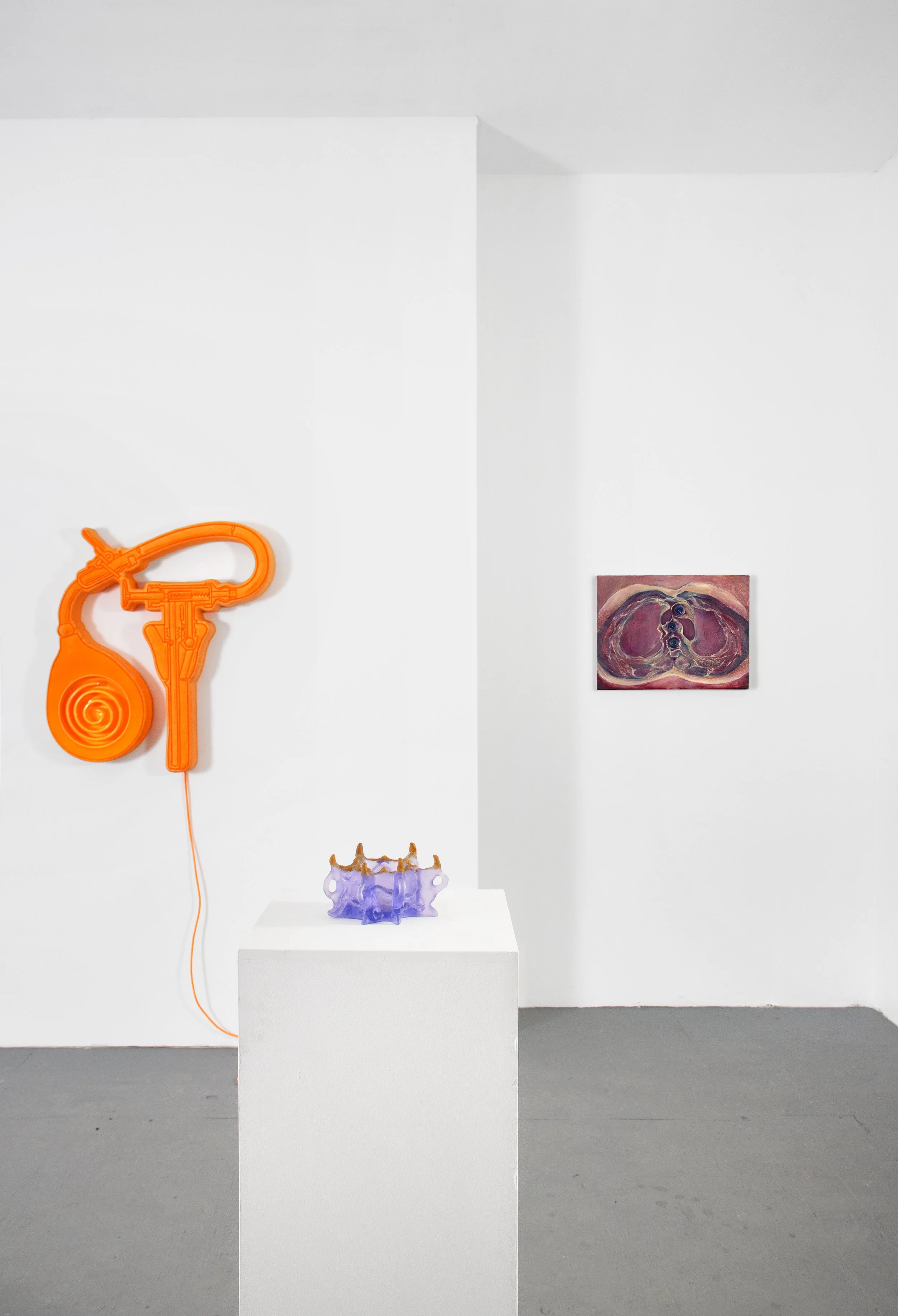 An art gallery with white walls displaying a large orange sculptural piece resembling a spiral phone, a purple glass sculpture on a white pedestal, and a square painting with swirling abstract shapes in shades of pink, purple, and white.