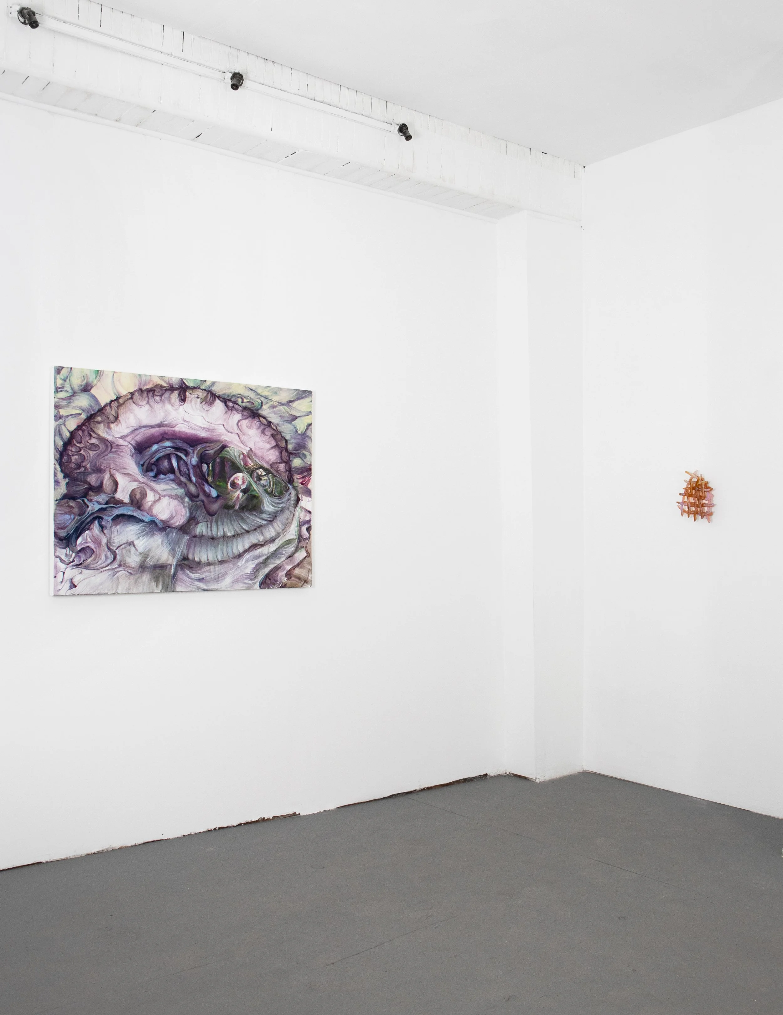 Art gallery wall with a large abstract painting of a spiral shape and smaller mixed media piece on a white wall.