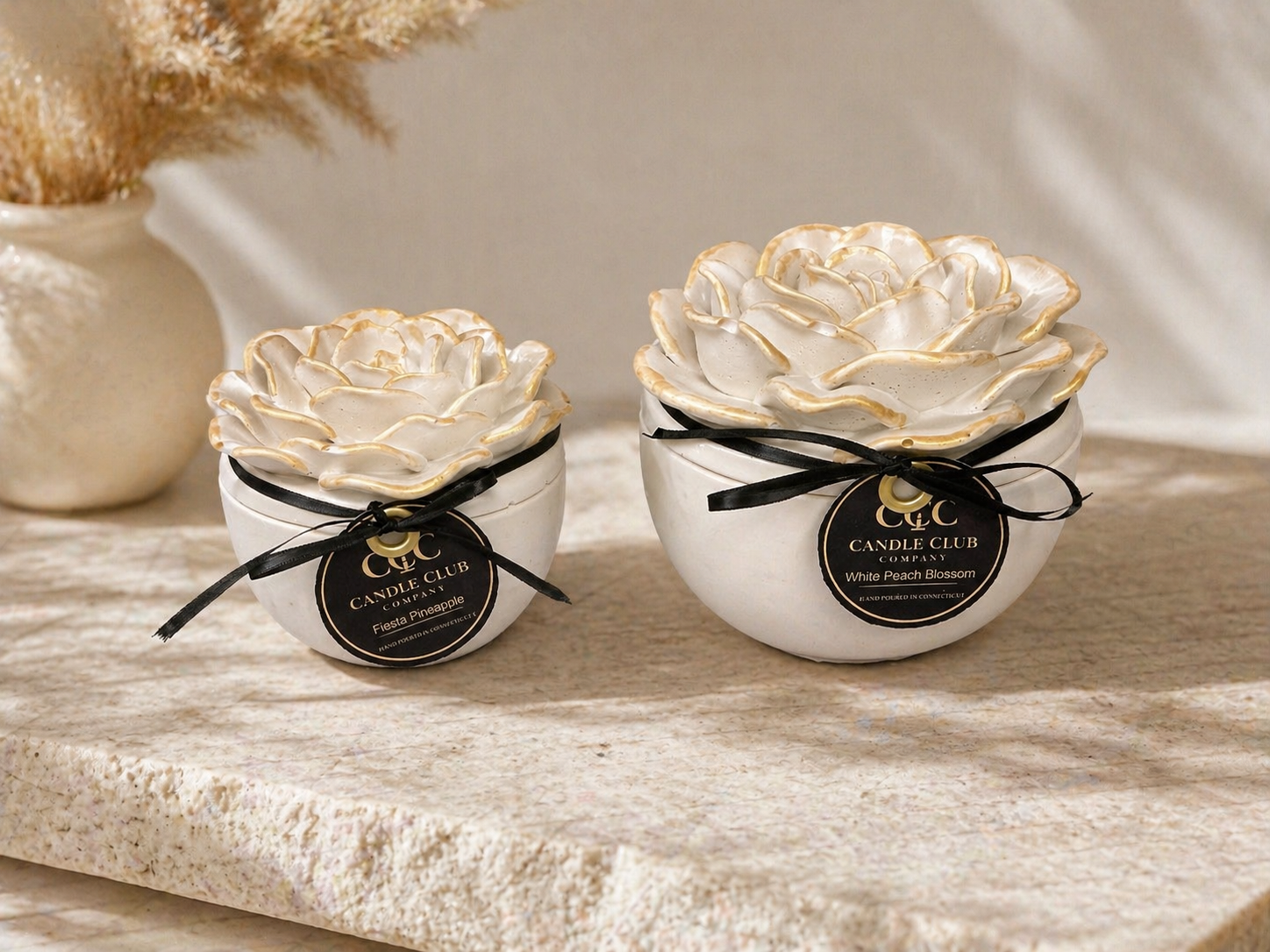 Two handcrafted floral vessel soy candles in 4 oz and 8 oz sizes styled on neutral stone background.