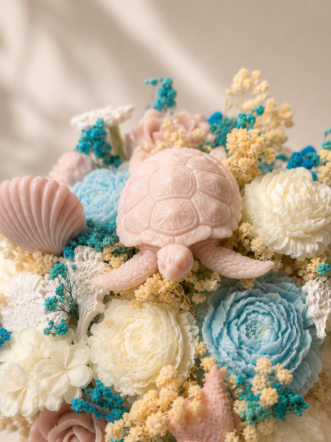 Close-up of handcrafted coastal floral candle bouquet with seashell and turtle details
