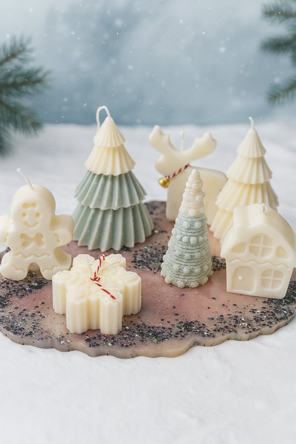 Handcrafted Christmas tree candles arranged in white ceramic trays filled with faux snow, created by Candle Club Company