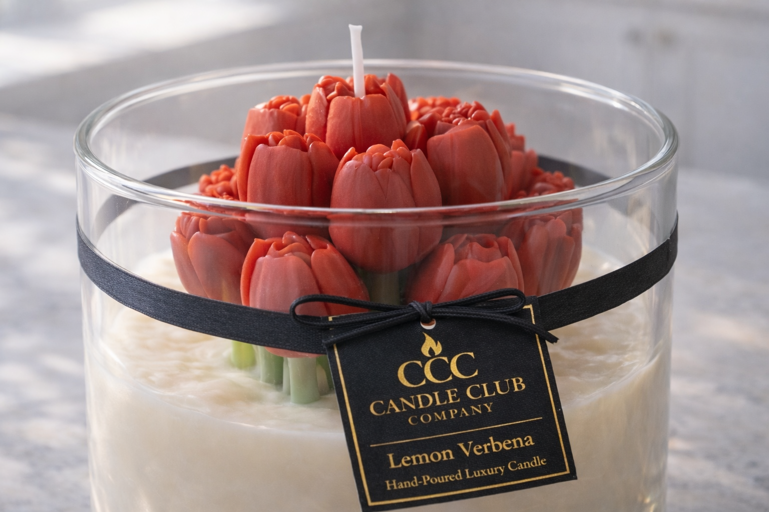 Hand-poured lemon verbena soy candle with red tulip wax flowers in a clear glass jar with luxury label