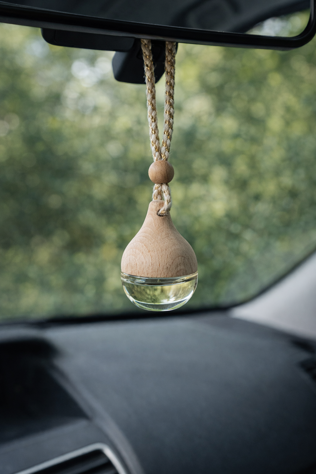 Hanging car diffuser displayed on rearview mirror with natural wood and glass design