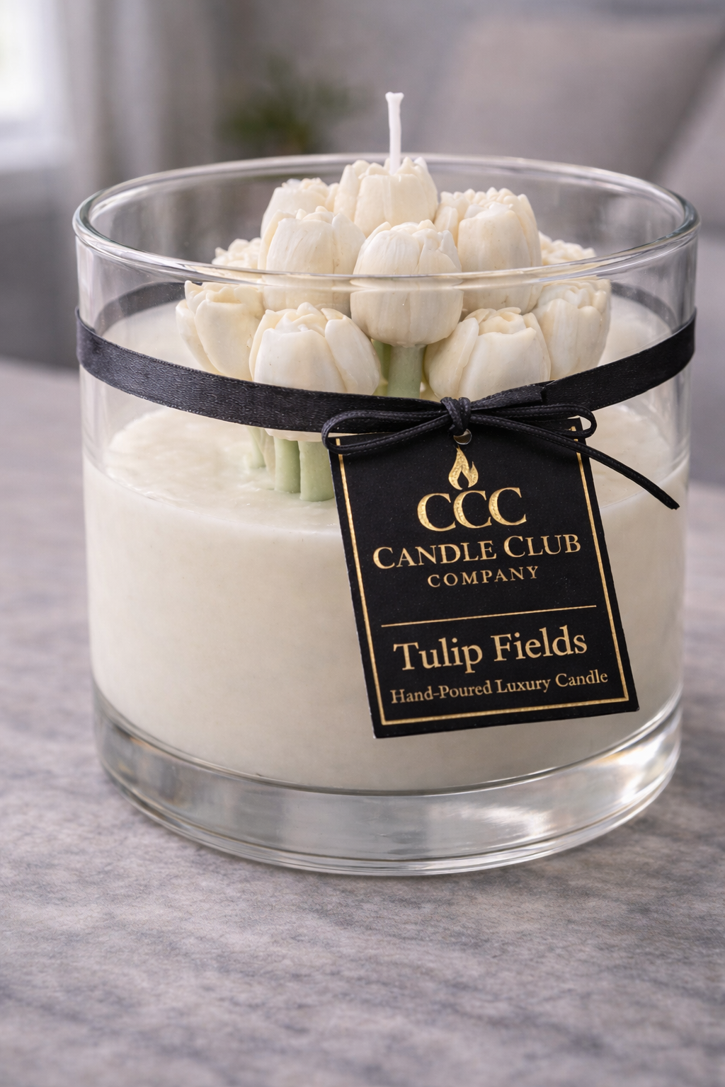 White tulip bouquet soy candle in clear glass jar with black ribbon and gold label, clean neutral background