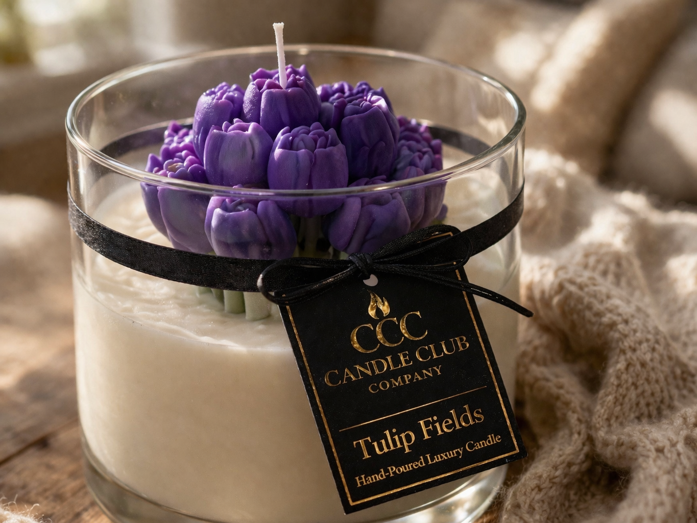 Luxury purple tulip bouquet soy candle in glass jar with black and gold label, styled in a cozy home setting