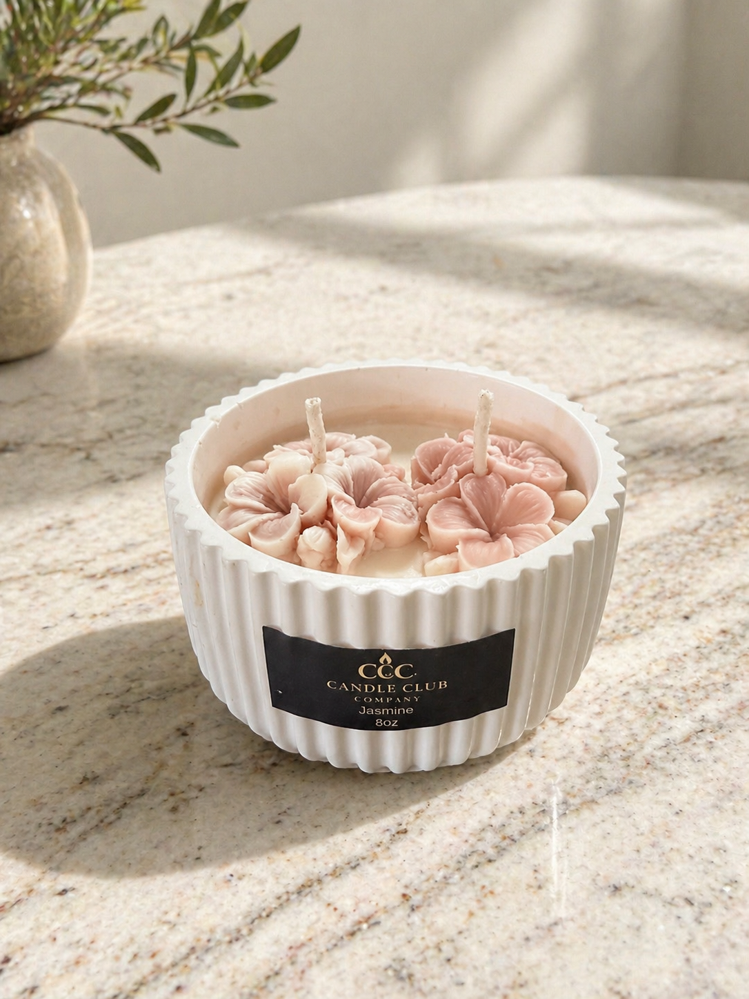 Luxury Floral Duo Candle – 10 oz in white ribbed vessel with blush floral wax embeds on marble surface in natural sunlight.