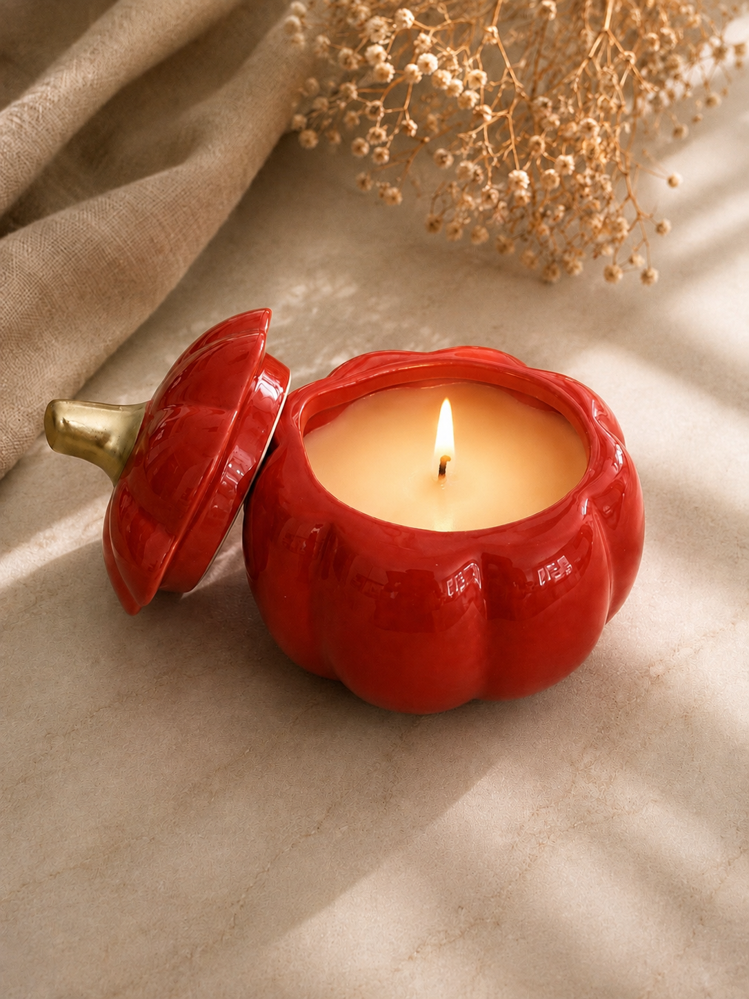 Lit Golden Harvest Pumpkin 8 oz soy candles in glossy orange ceramic with gold stems, hand-poured in Farmington, Connecticut.