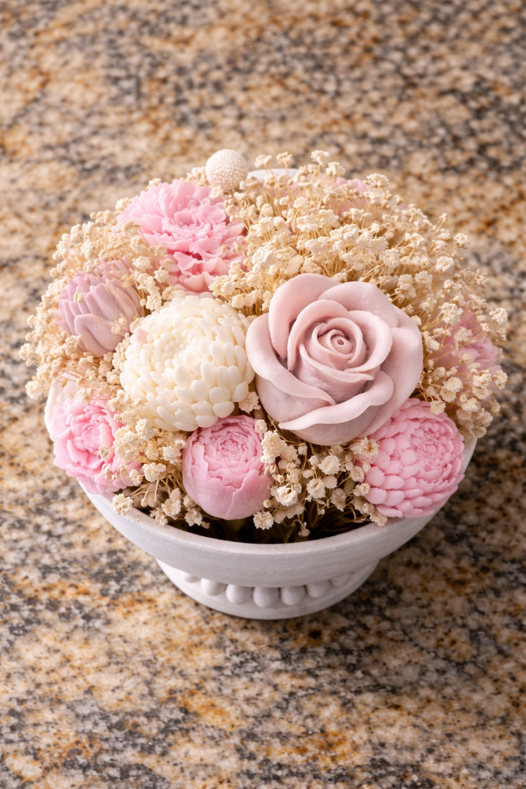 Top view of large floral candle centerpiece with over 30 hand-poured wax flowers in neutral pink and cream tones in decorative vessel
