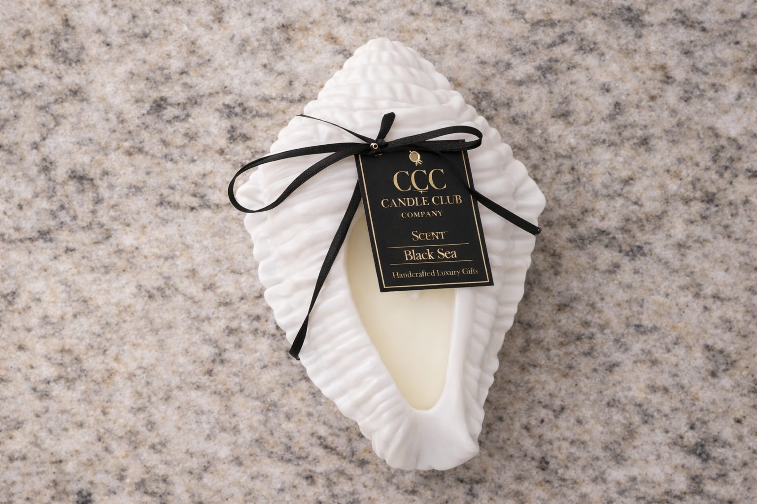 Top view of sculpted wave candle with minimalist design and centered wick on marble background