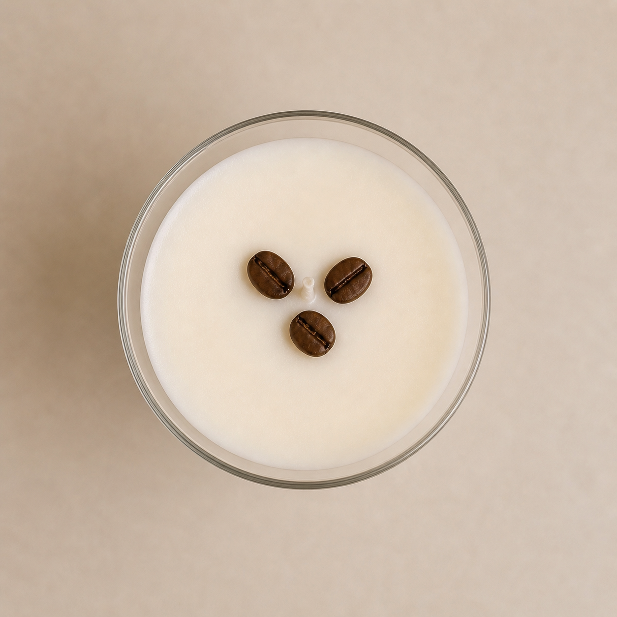 Top view of espresso martini candle with smooth cream wax surface and three coffee bean accents in a glass martini vessel.