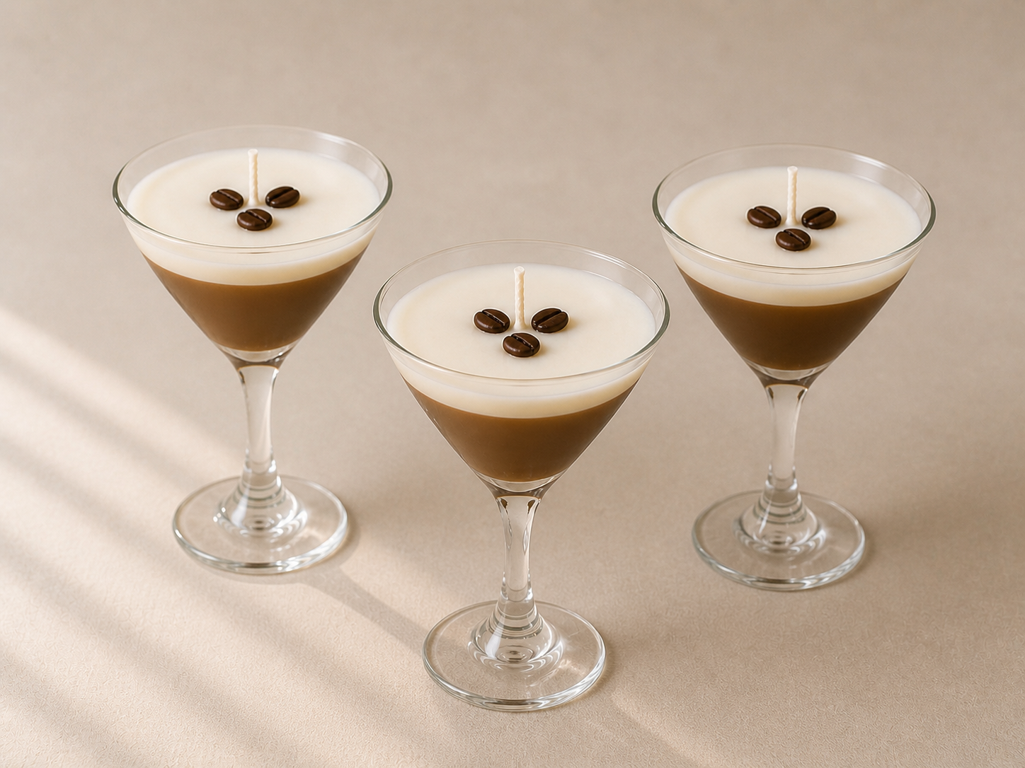 Set of three espresso martini soy candles in martini glasses with coffee bean toppings styled on a soft neutral background.