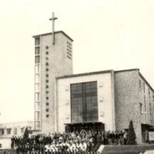 Black and white photo of a large church building with a prominent cross on top, surrounded by a crowd of people. YMCA, Tsim Sha Tsui, Hong Kong