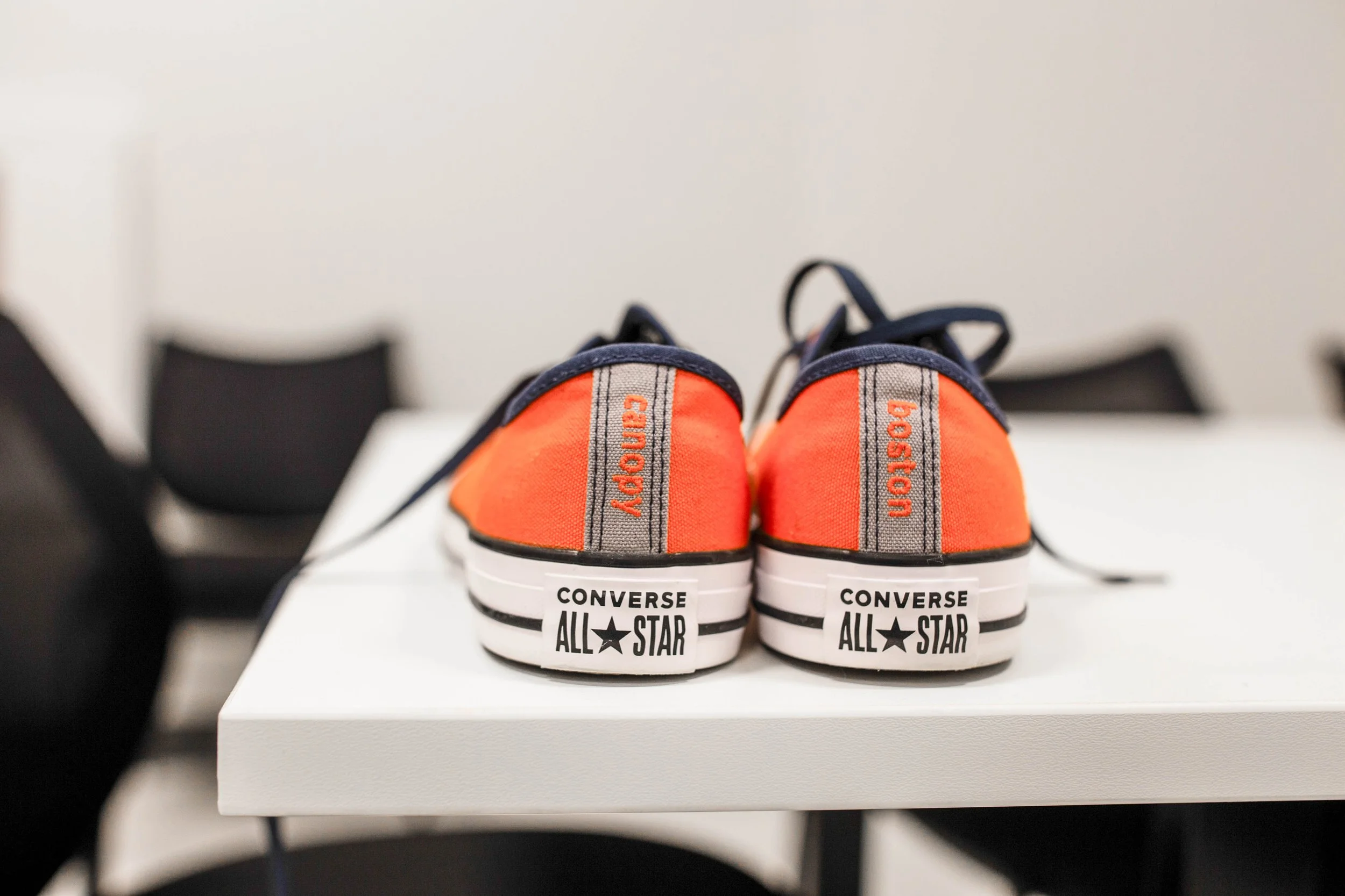 Pair of orange and navy blue Converse All Star sneakers on a white table.