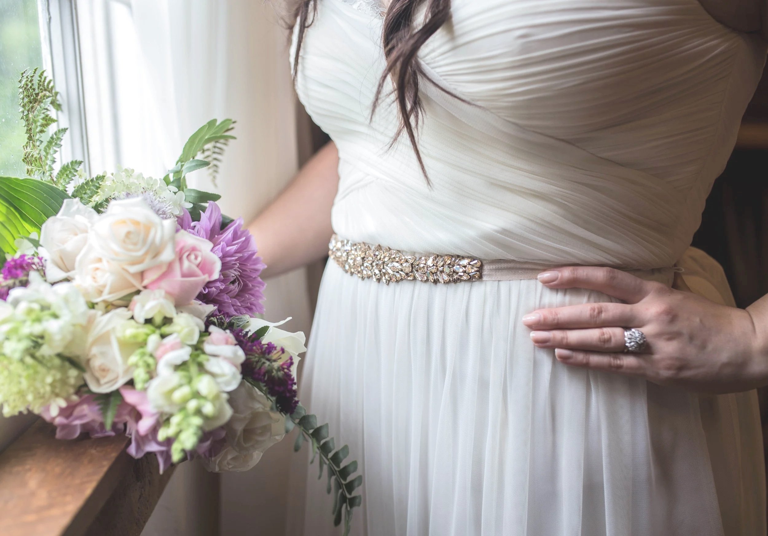A young woman in a red and gold princess dress and tiara smiling as she dances with a young man in a black suit at a formal event, with women clapping and taking photos in the background.