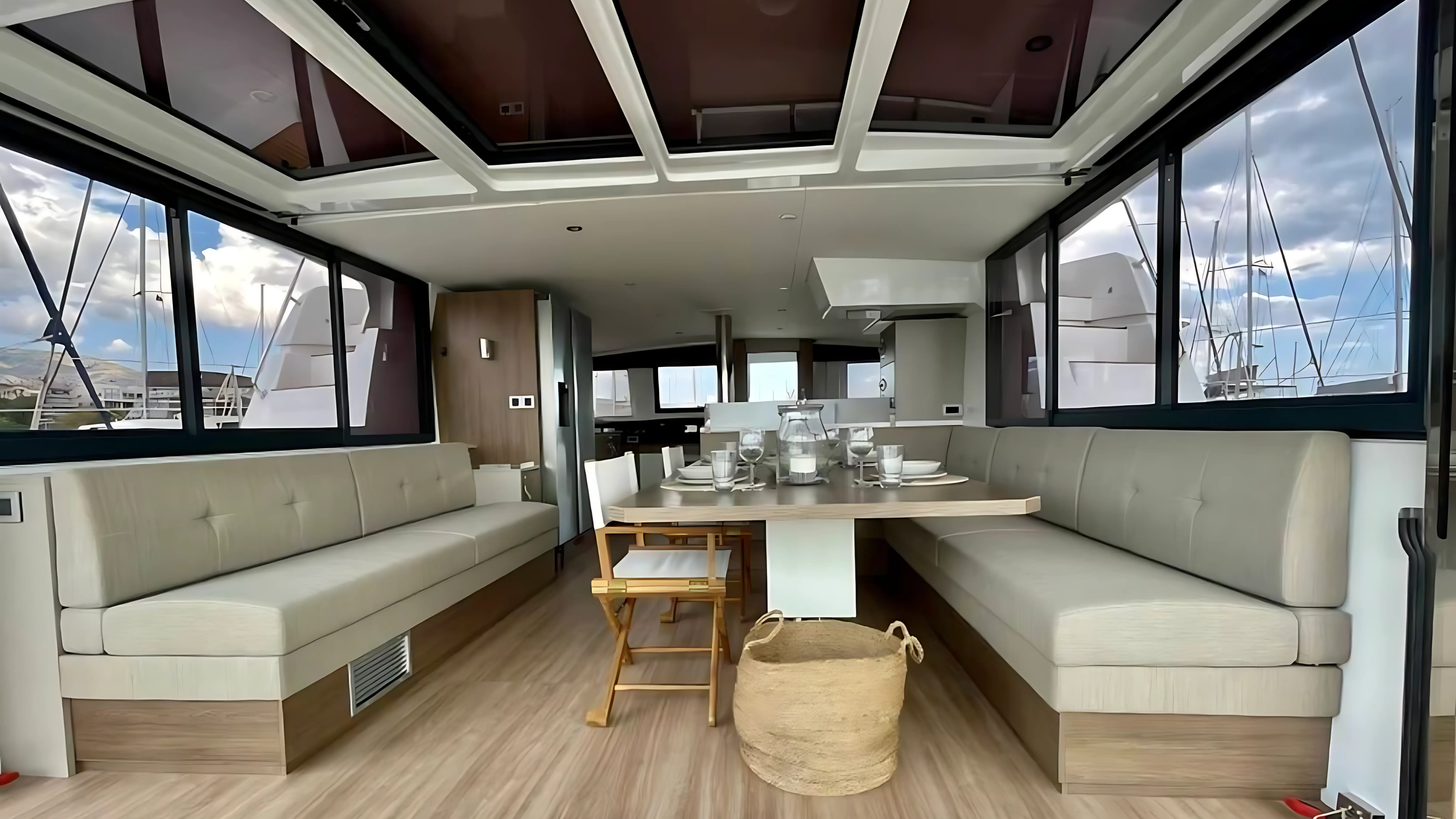 Interior of a yacht with plush seating, dining table, windows, and modern decor.