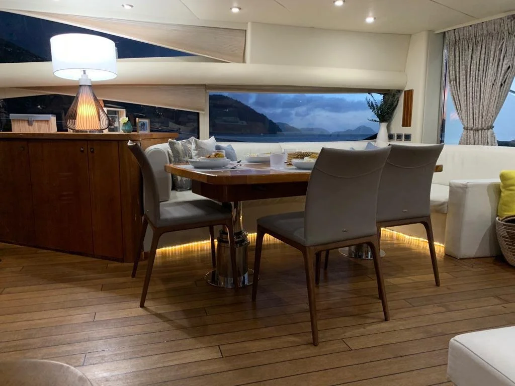Interior of a luxury yacht dining area with wooden floor, dining table, and chairs.