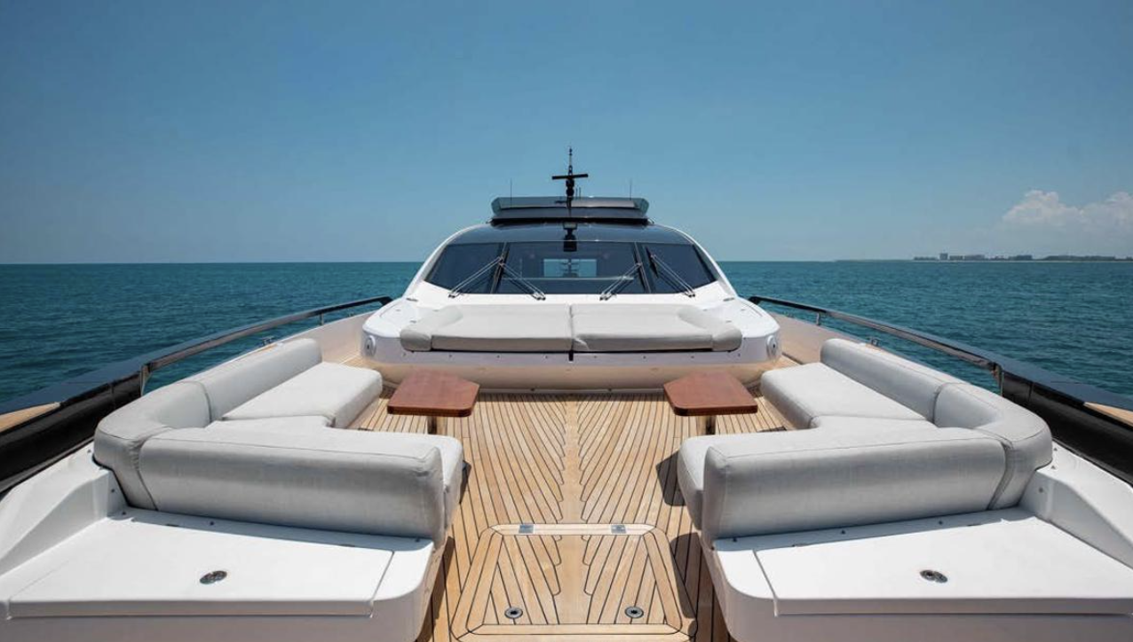 Luxury yacht deck with sofas, wooden flooring, and sea view under clear sky.