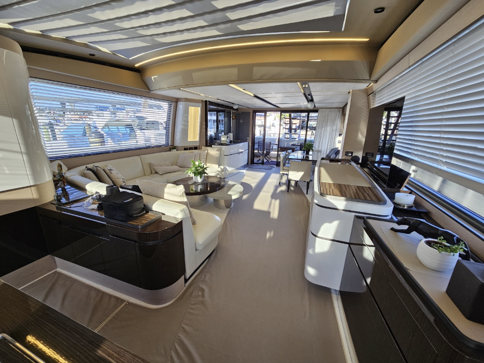 Modern yacht interior with sofas, dining table, and large windows.