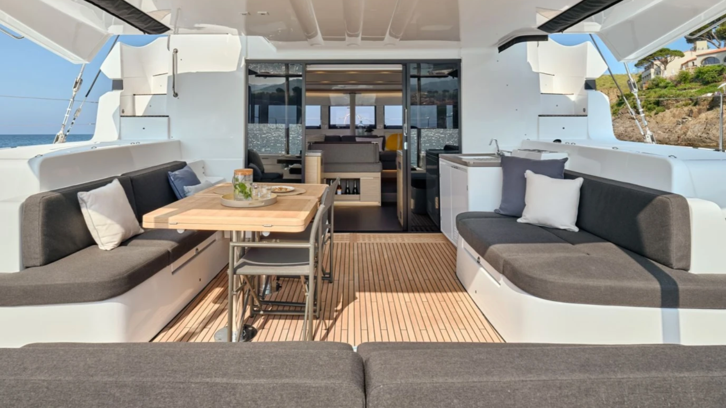 Luxury yacht interior with sofas, wooden table, and sea view.