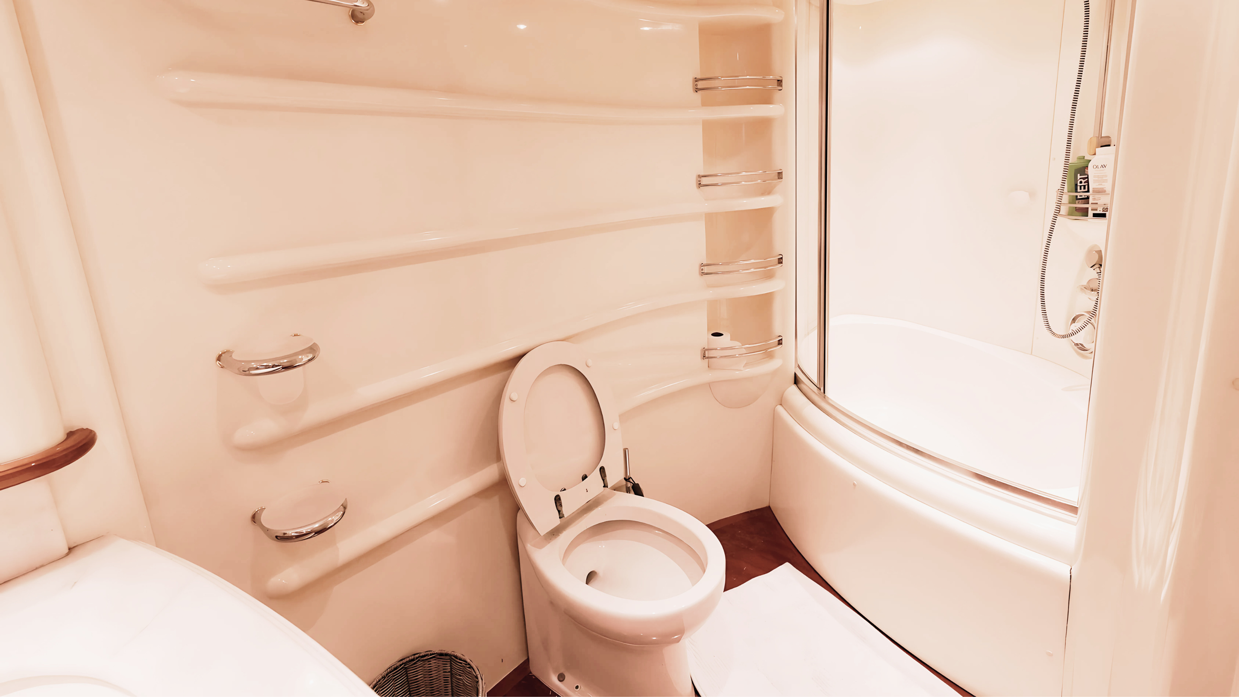 Modern bathroom with toilet, curved bathtub, and wall shelves.