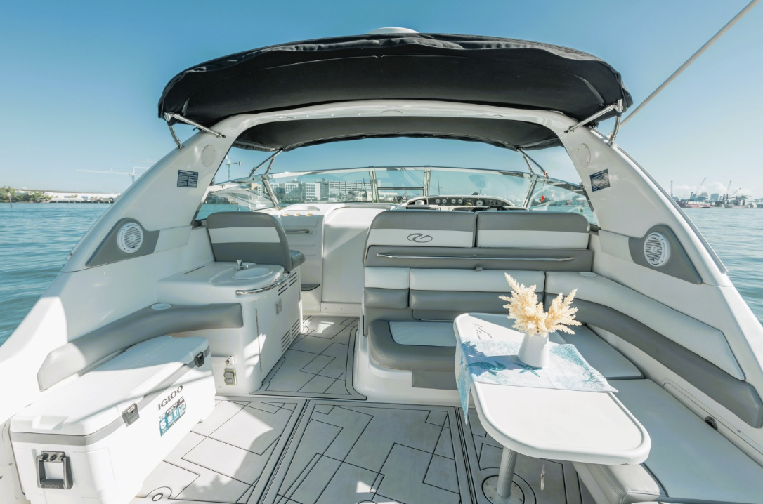 Luxury yacht interior with seating area and table, overlooking water and cityscape.