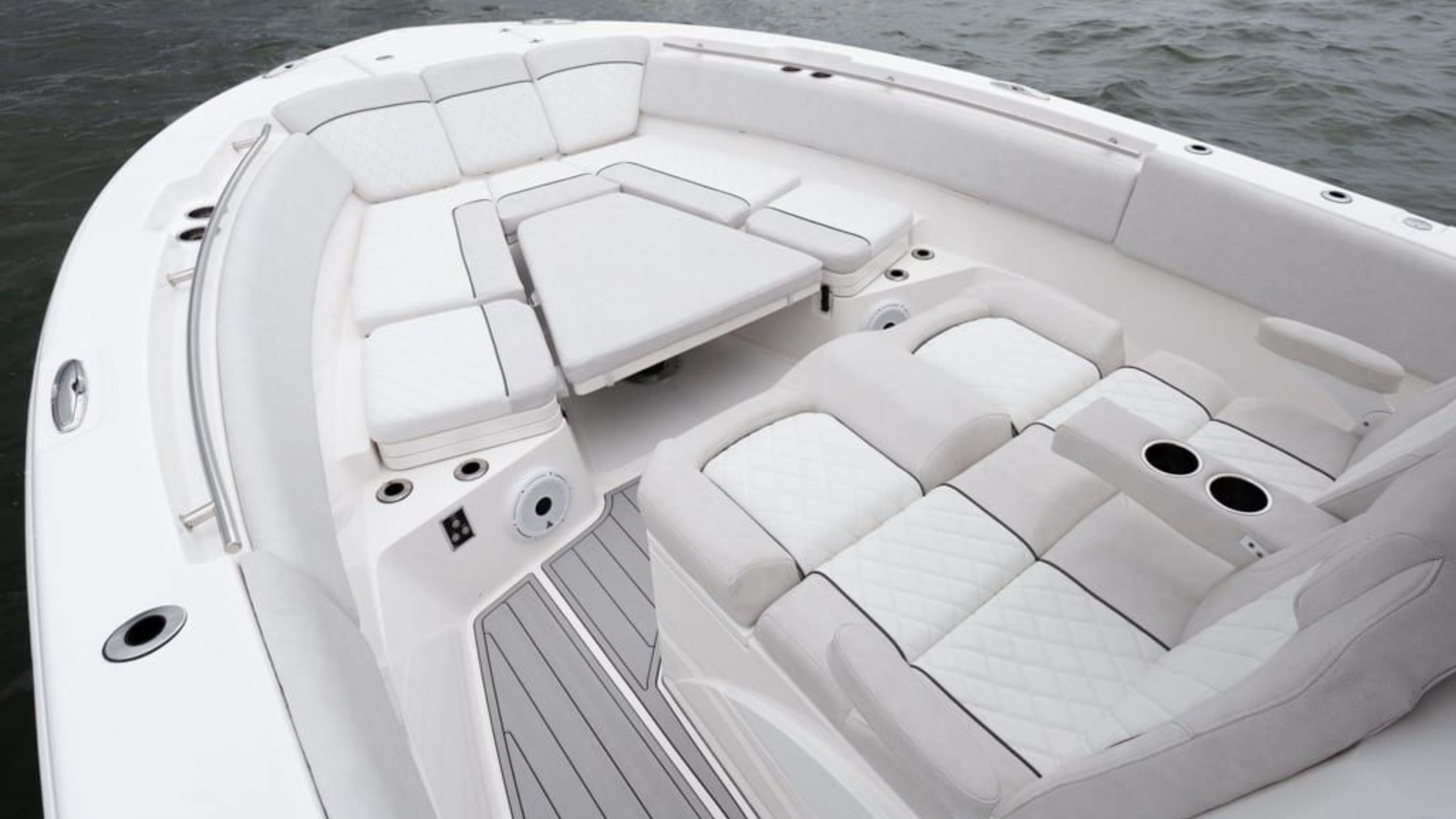 luxury boat interior with white cushioned seating and cup holders