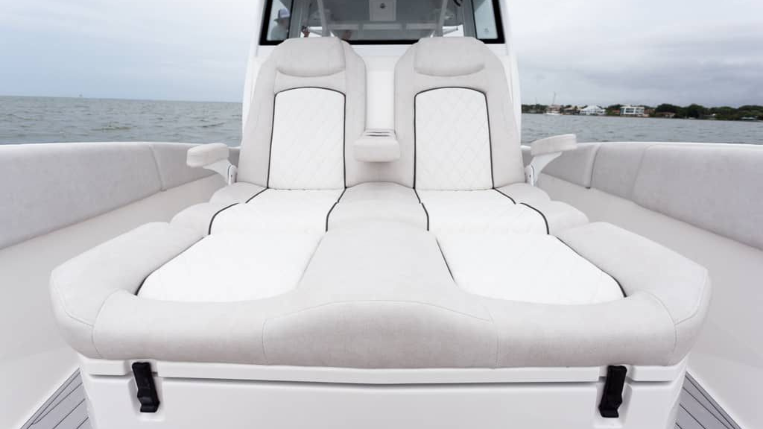 luxury boat interior seating with white cushions on a calm sea
