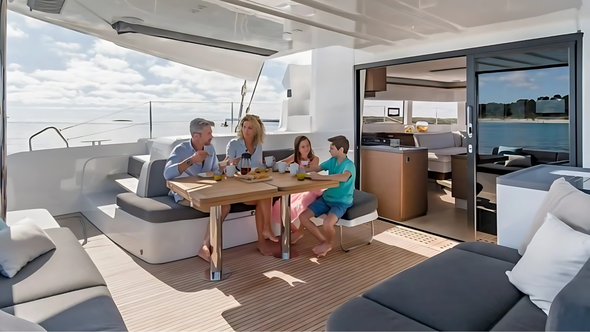 Family dining on a yacht with open cabin and ocean view.