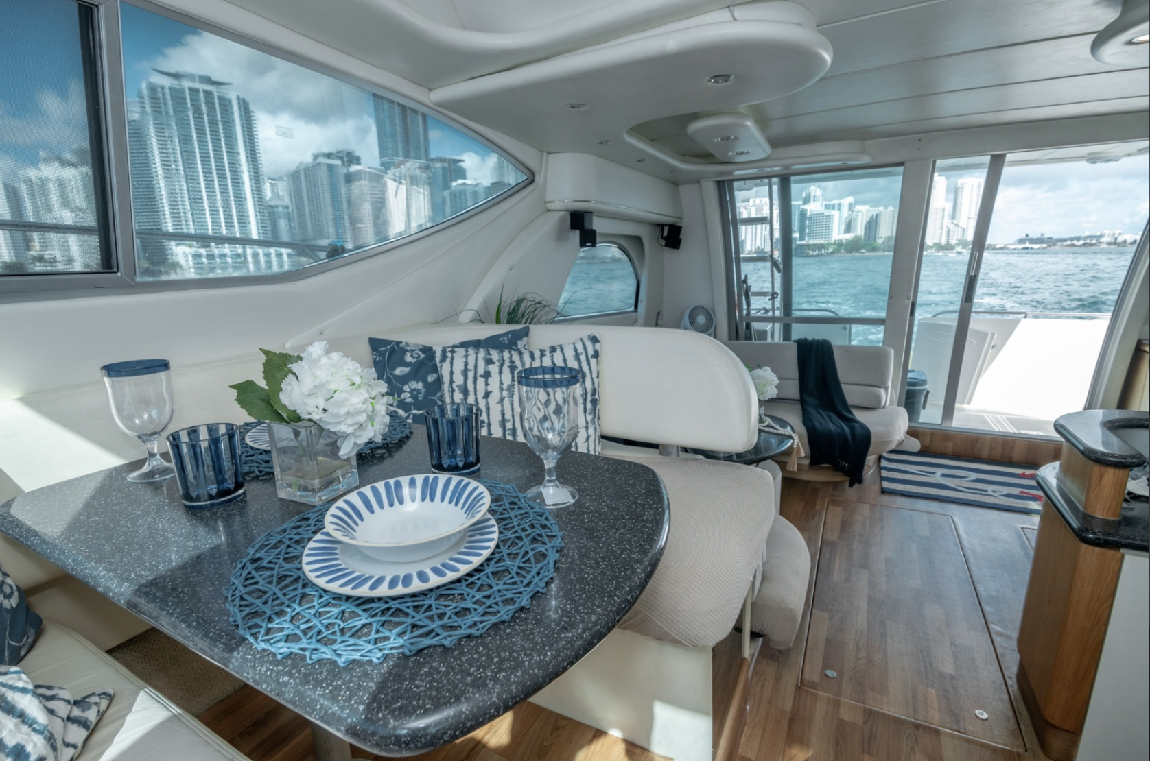 Luxury yacht interior with dining and seating areas, stylish decor, ocean view through windows.