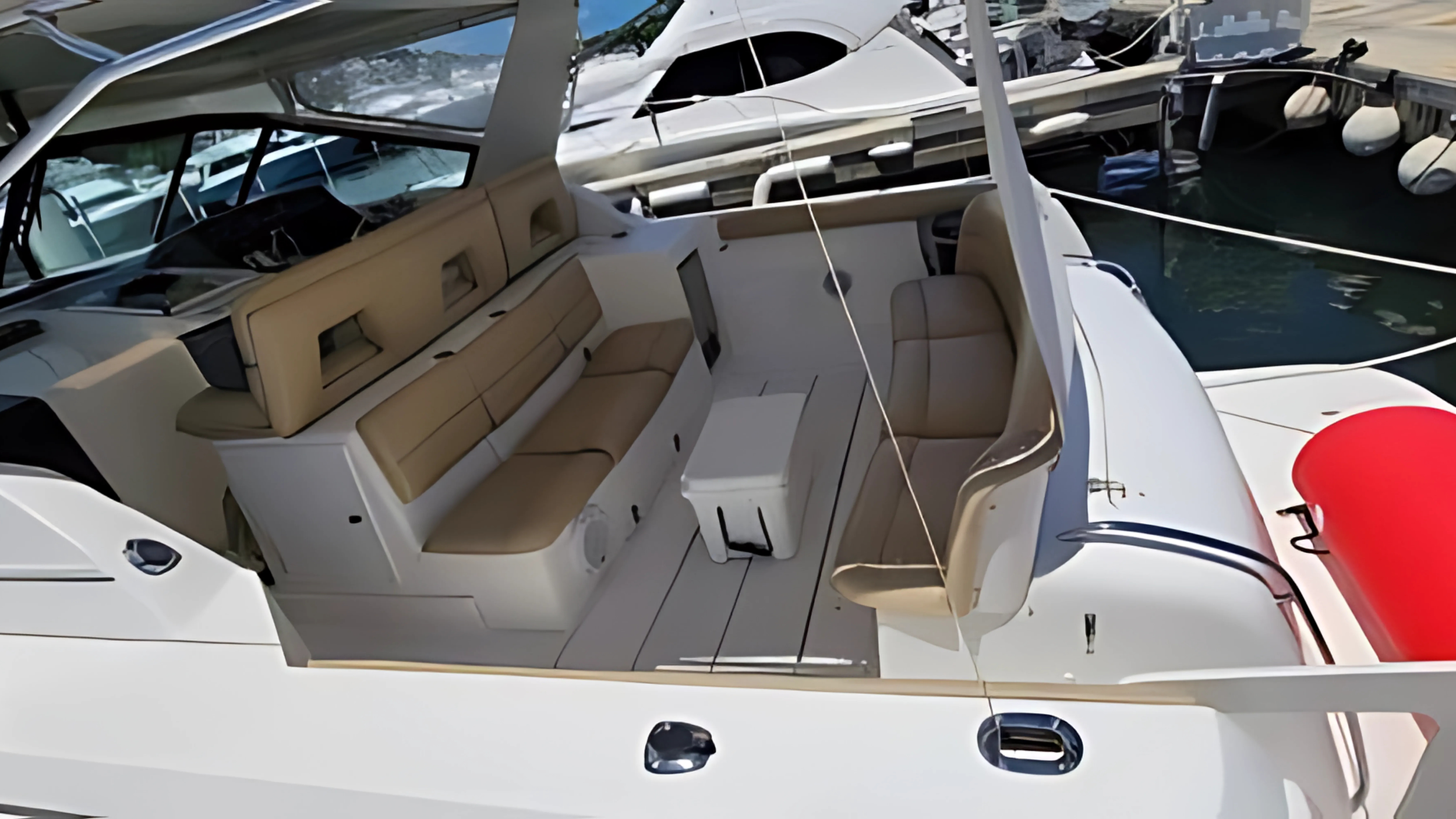 View of the interior and deck of a luxury motor yacht docked at a marina with other boats in the background.