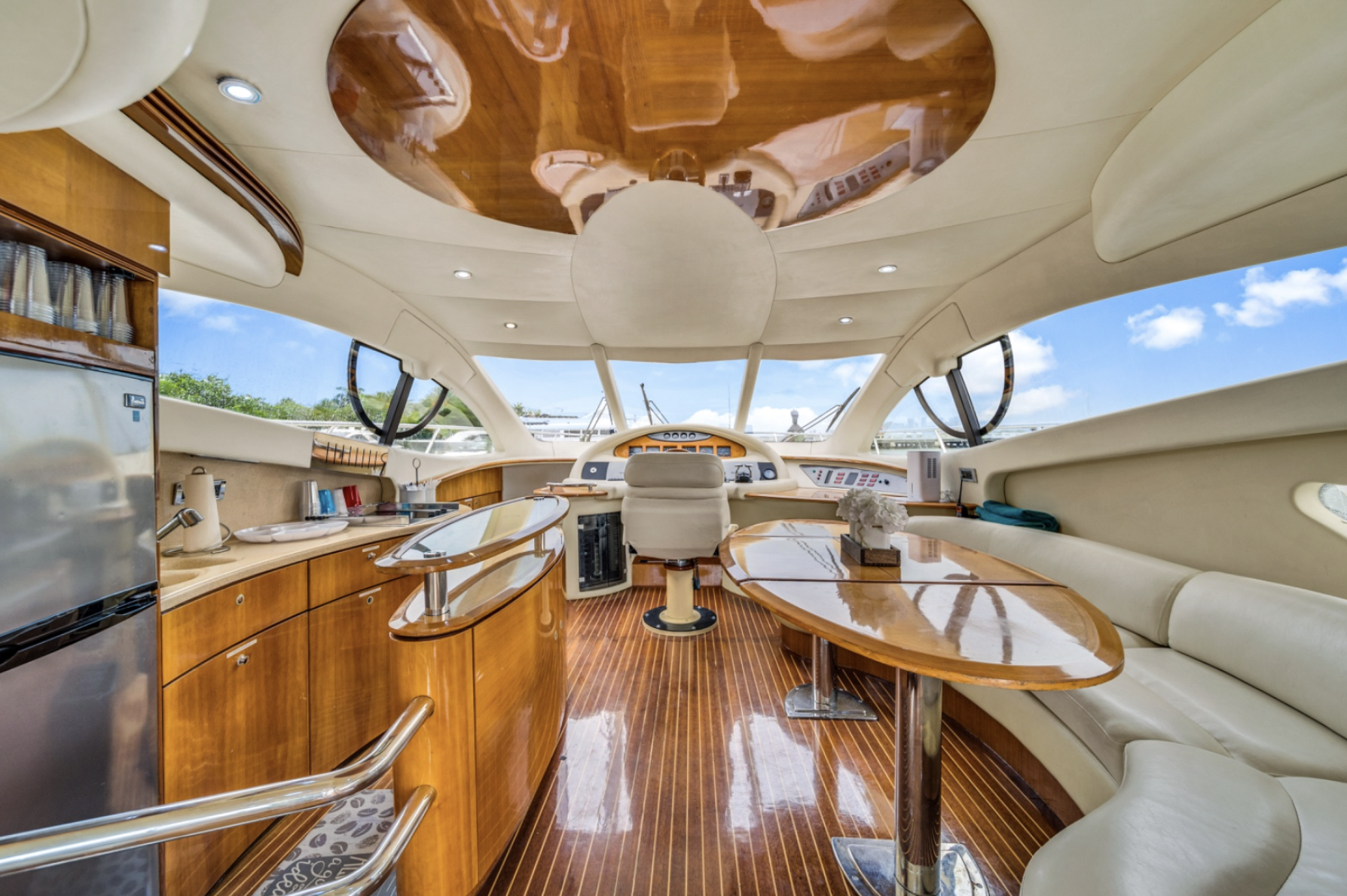 Luxury yacht interior with wooden finishes, steering console, and seating area.