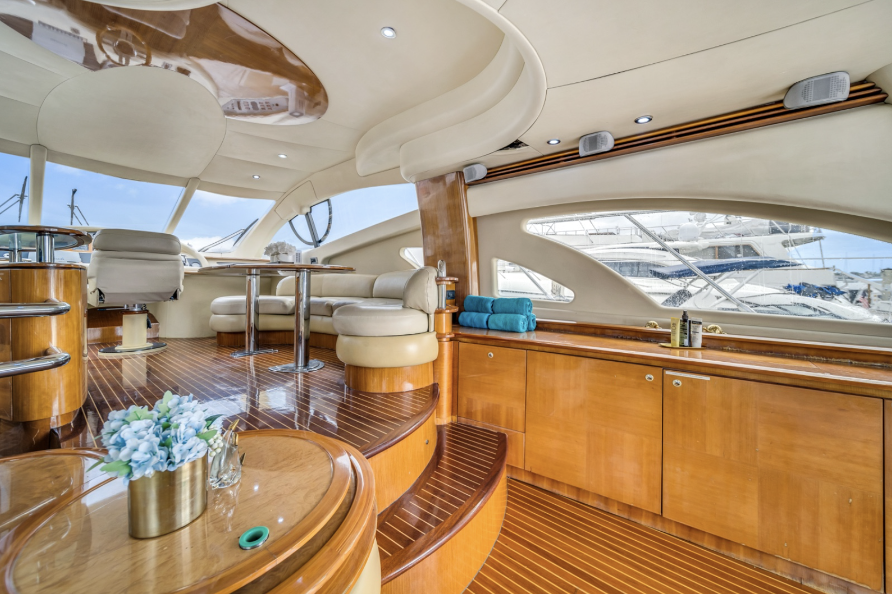 Luxury yacht interior with leather seating, wooden flooring, and ocean views through large windows.