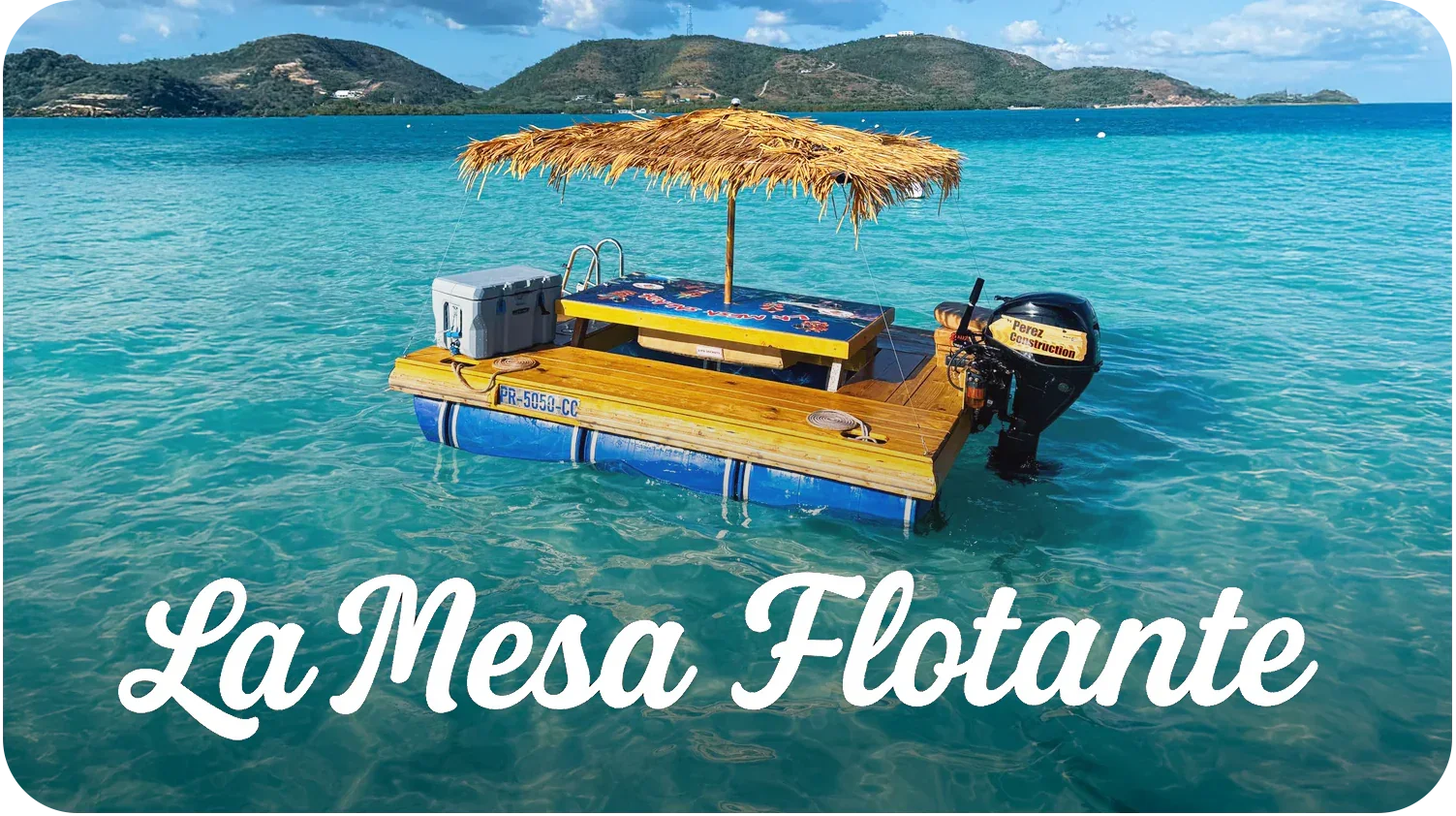 A floating wooden platform with a thatched roof, an ice cooler, and a small outboard motor, floating on clear blue water with hilly islands in the background. Text overlay says "La Mesa Flotante."