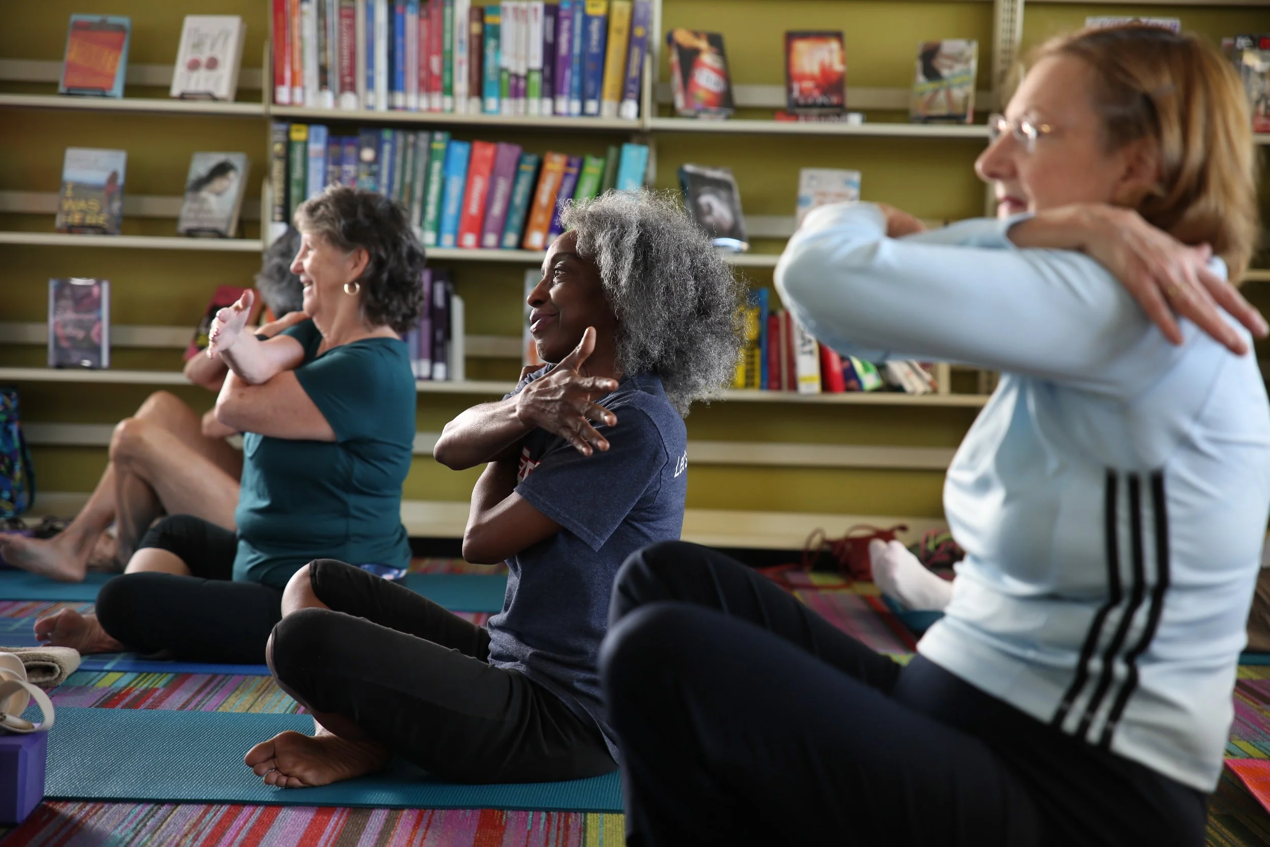 Group of diverse women practicing yoga or meditation in a library.