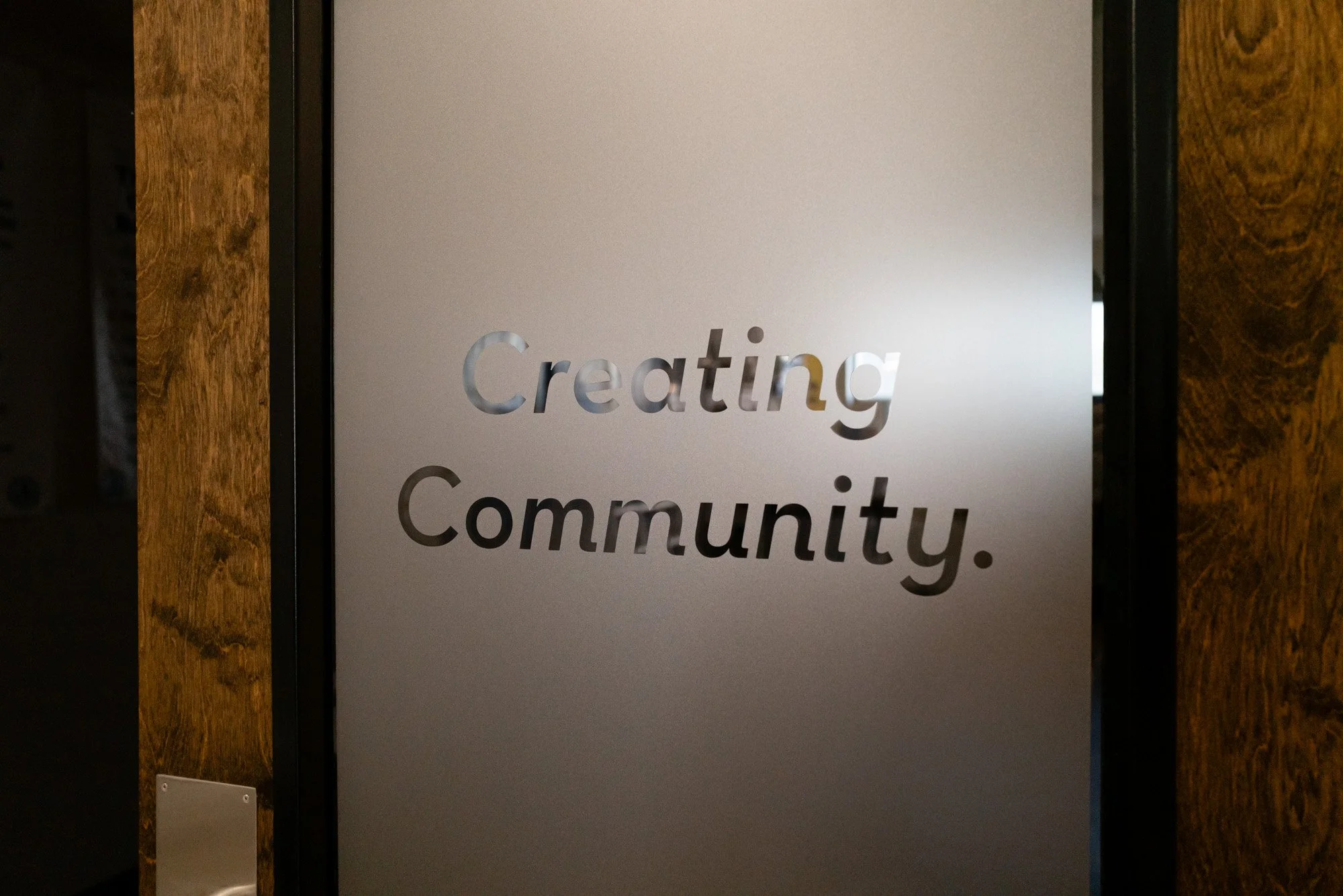 frosted glass door with the words creating community 