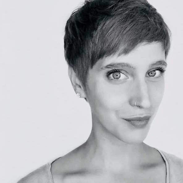 A woman with short hair, visible in black and white, looking at the camera with a slight smile.