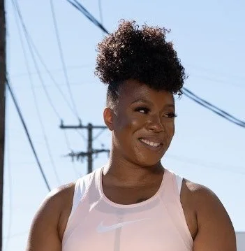 A woman smiling outdoors with power lines in the background.