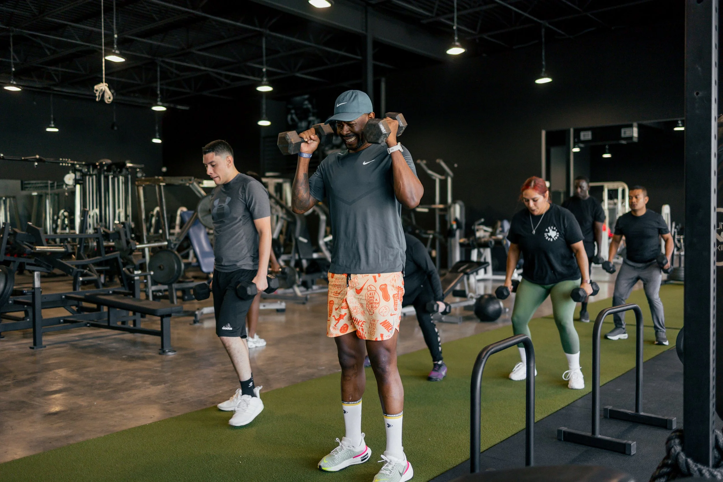 People doing a workout class at a gym, lifting weights and using equipment.