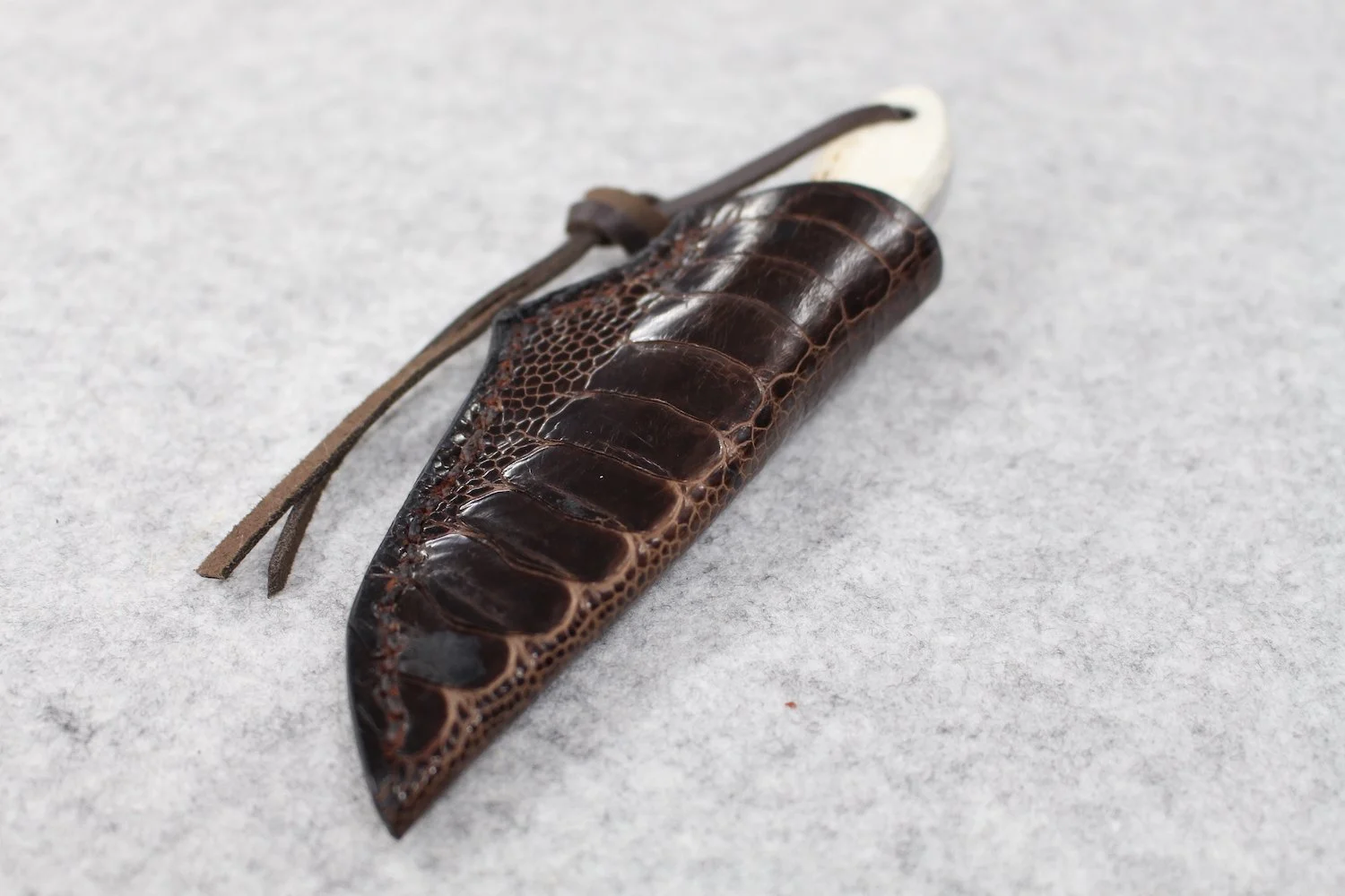 A hair clip designed to resemble a crocodile or alligator, made from dark, glossy, textured material with a leather strap detail.