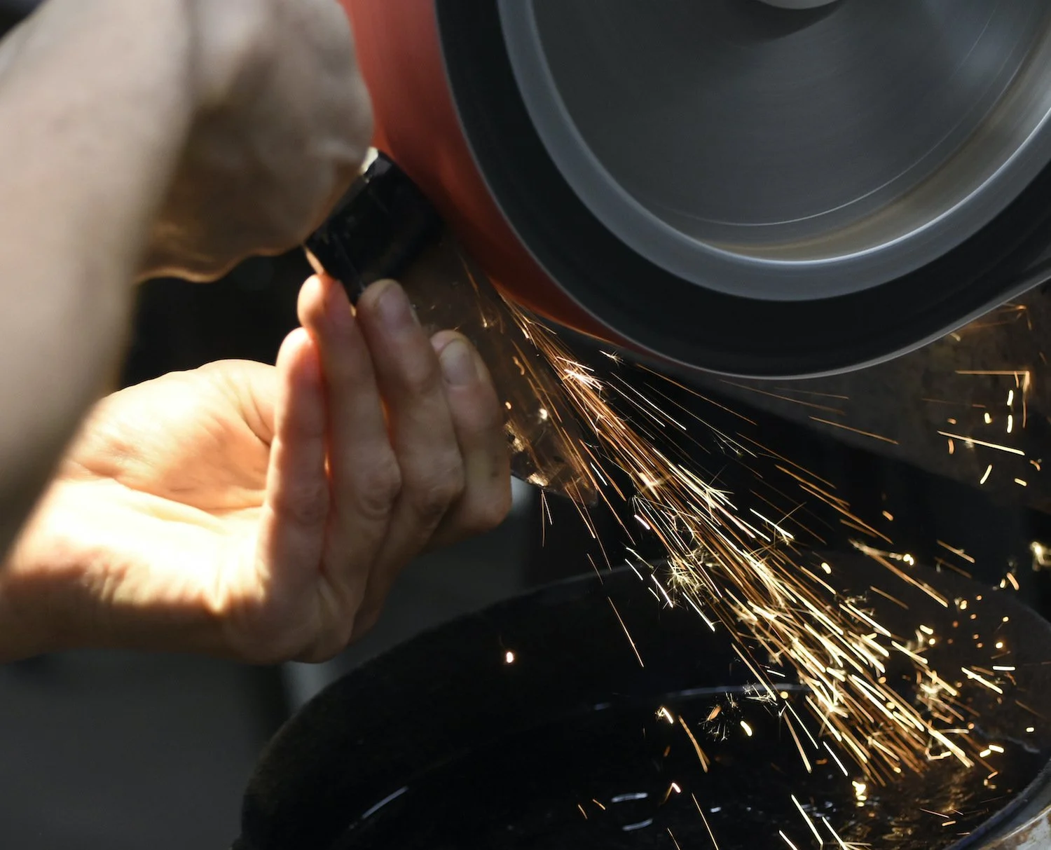 Woman hands working on the backstand to shape a handmade folding knife.