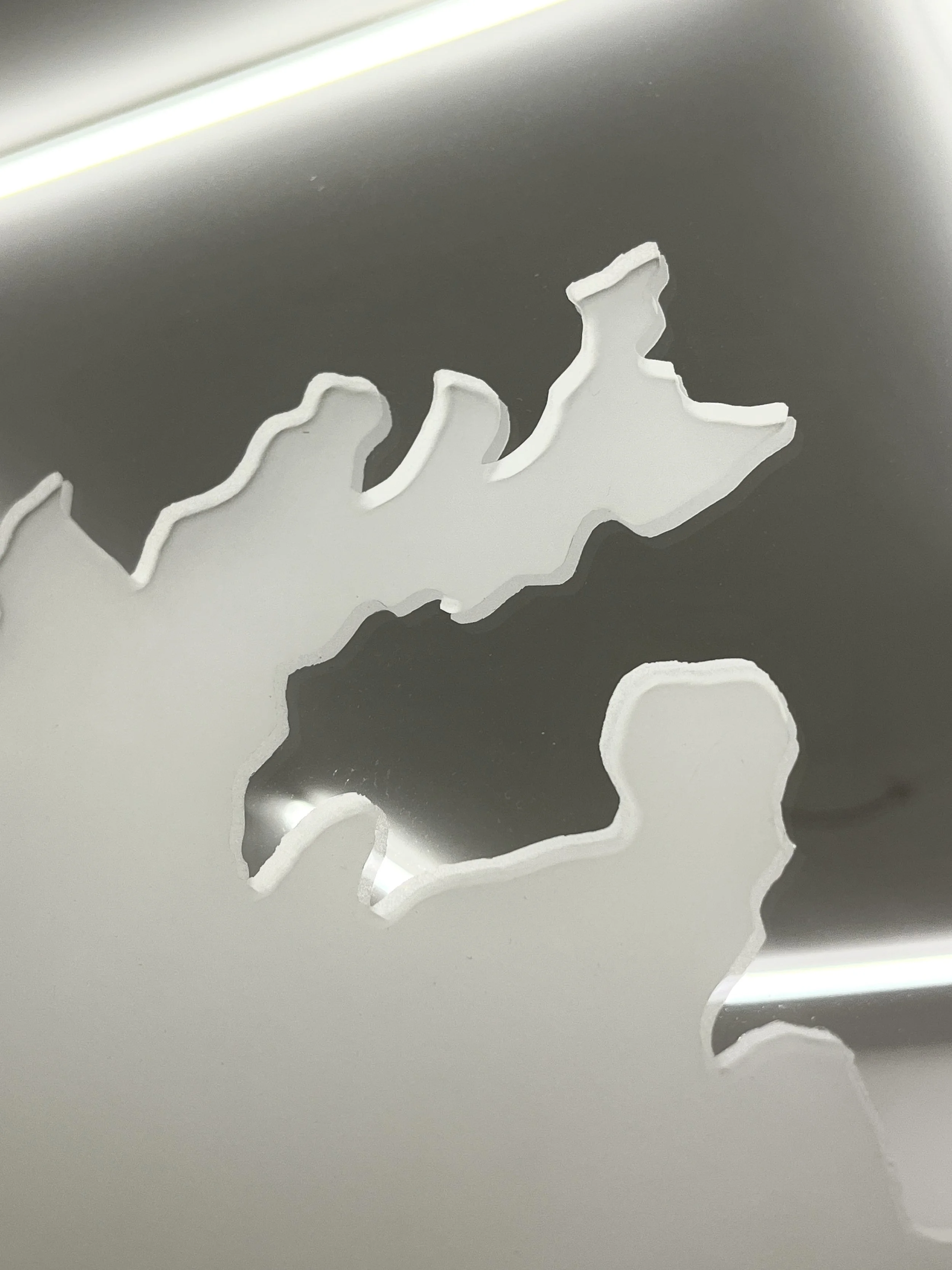 Close-up of a matt abstract cut-out design on a mirror.