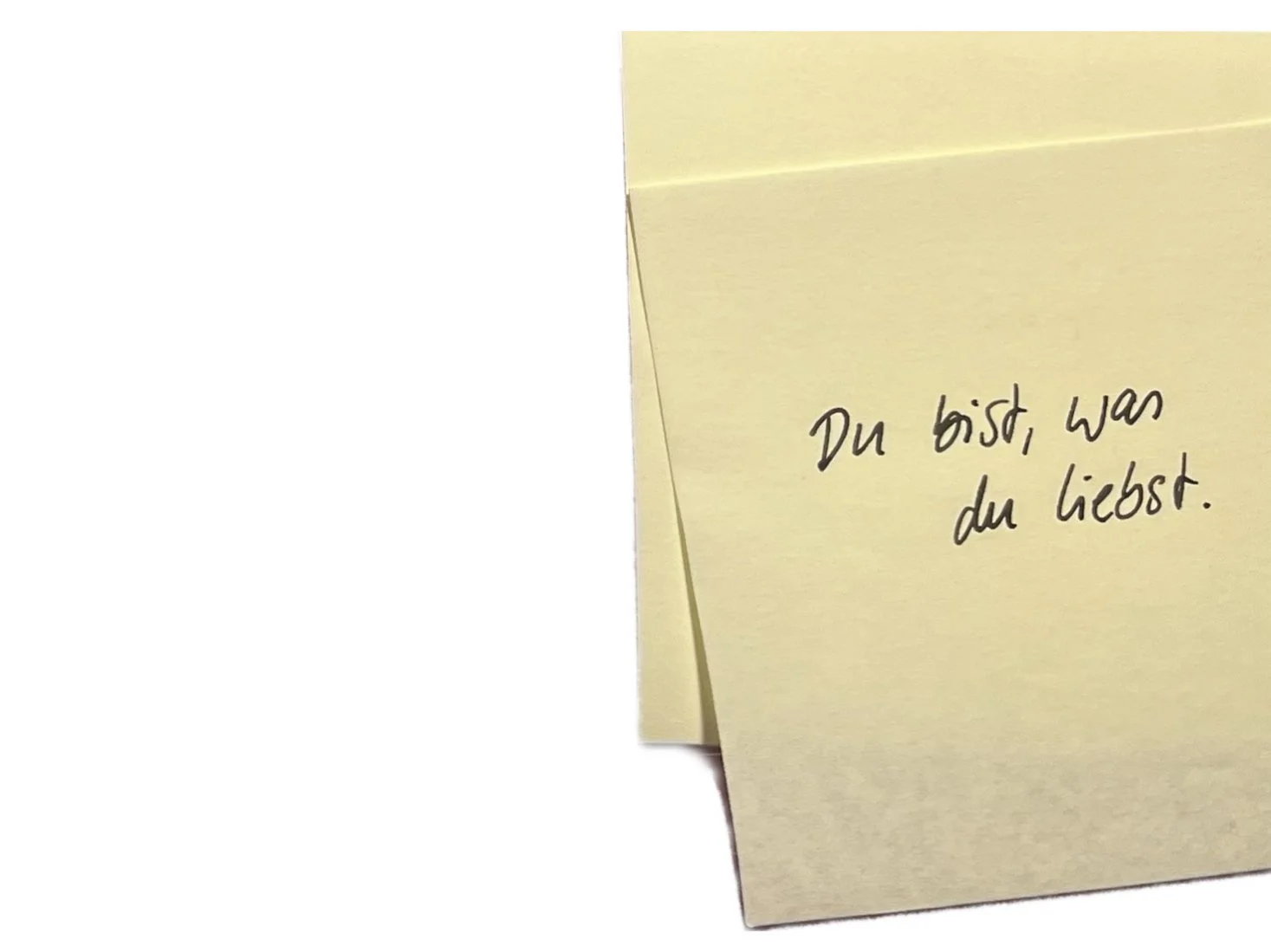 Yellow sticky notes with handwritten German text that reads: "Du bist, was du liebst."
