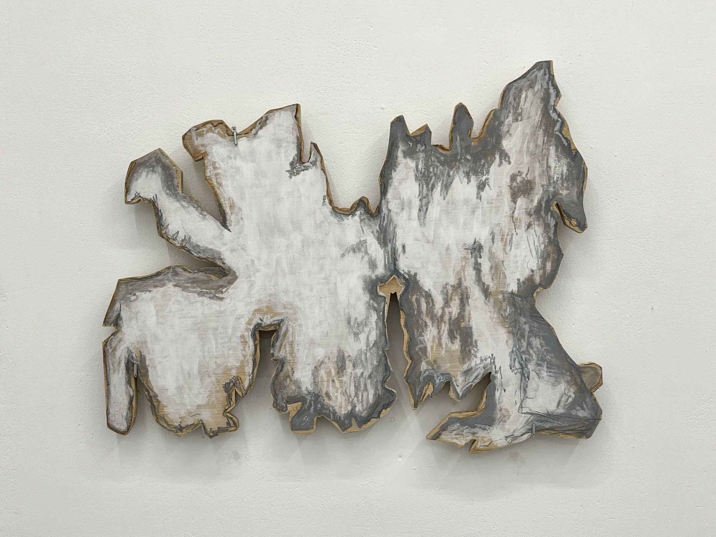 Decorative wooden wall art, painted in white, gray, and brown tones, mounted on a plain light-colored wall.