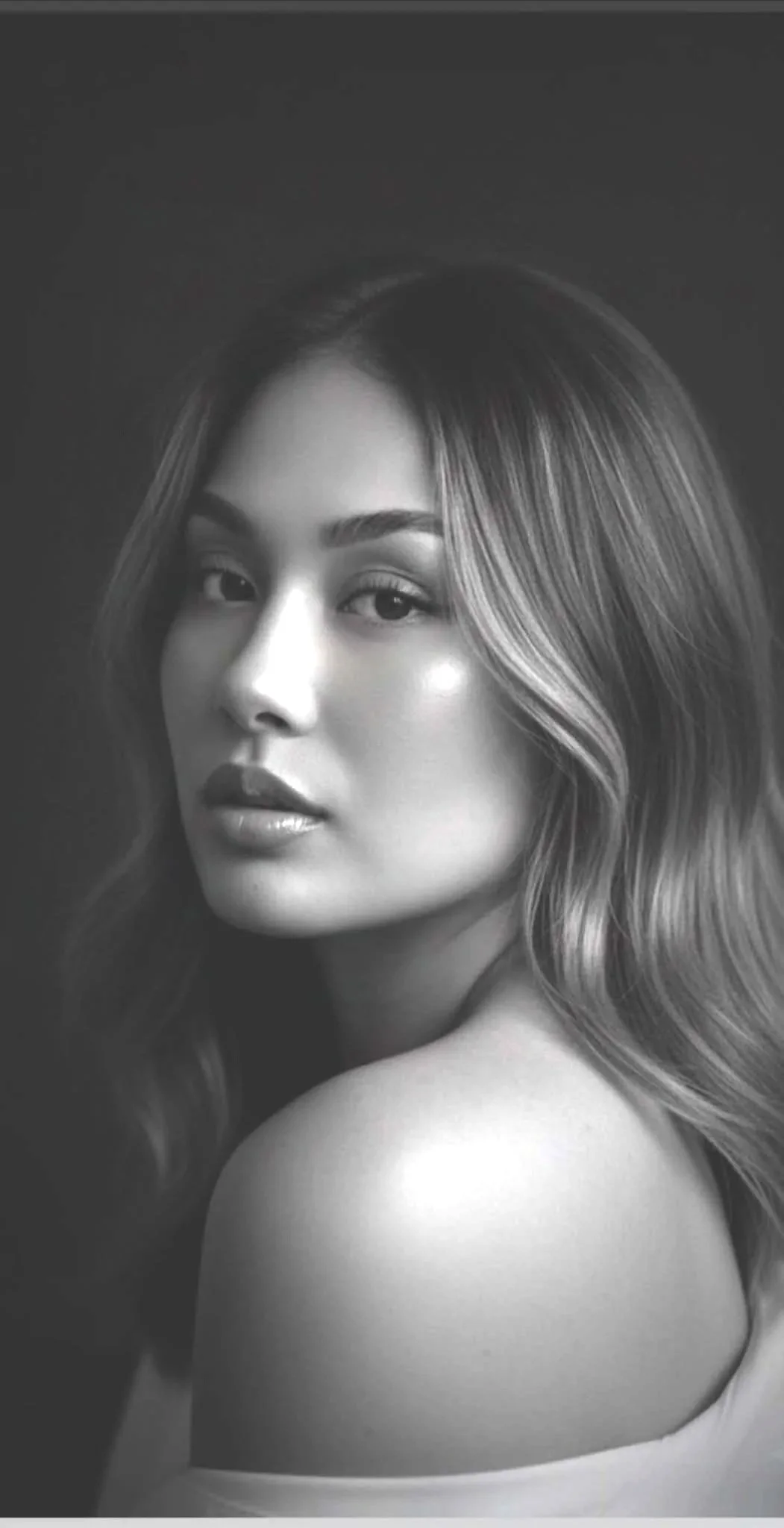 Black and white portrait of a woman with wavy hair looking over her shoulder.